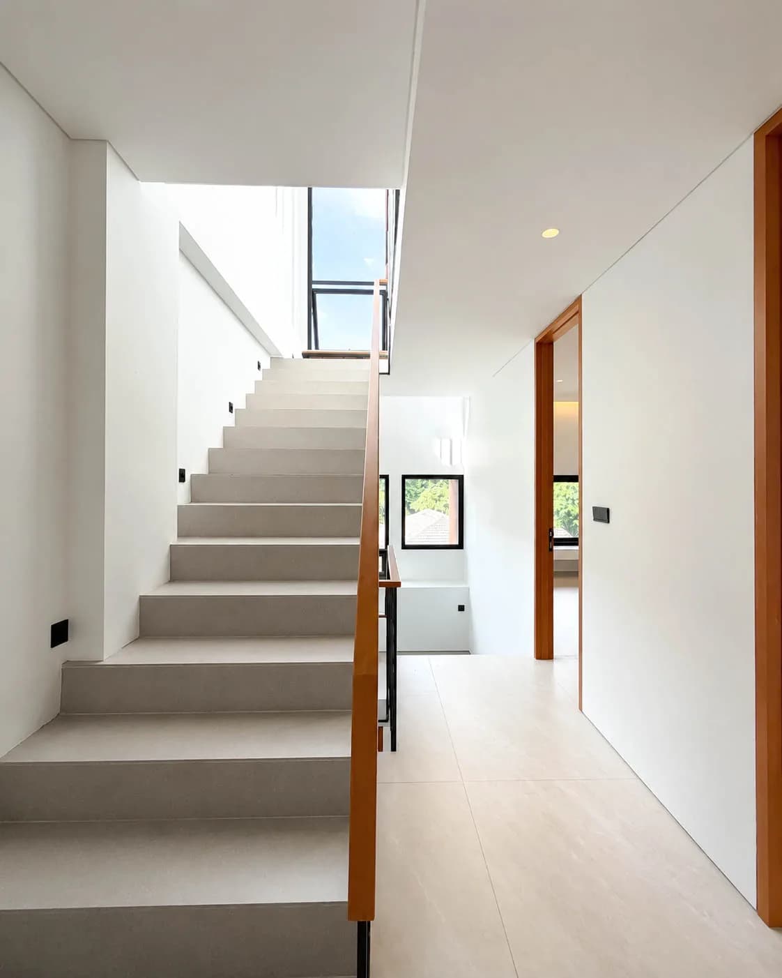 Daylight on the staircase: grey treads and a timber handrail rising towards a skylight