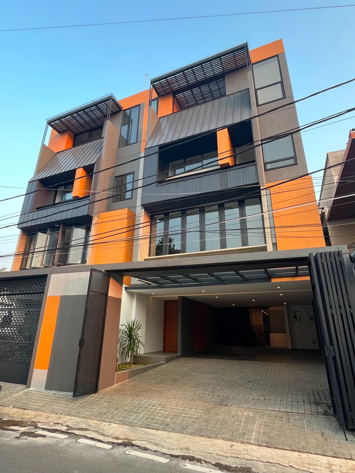 The four-storey house from the street, seen at an angle: orange, grey and timber facade above the open garage